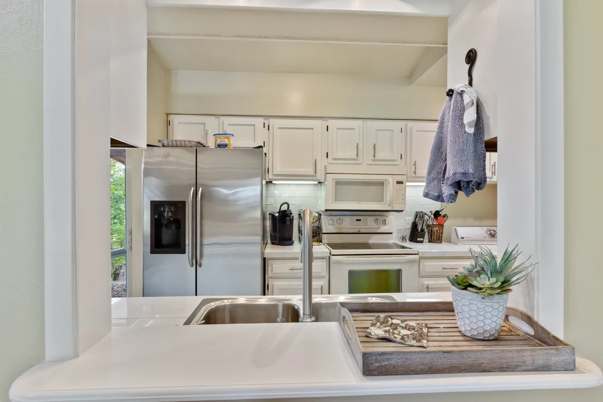 A welcoming kitchen scene with a stainless steel refrigerator, kitchen sink, and appliances, reflecting a space prepared for shared meals and easy routines. The modern, homey elements hint at convenient amenities like the Pack Less Program™.