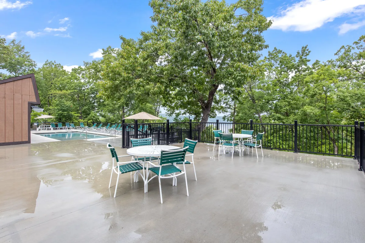 A vibrant scene of a swimming pool surrounded by outdoor seating and lush greenery. The setting is lively yet relaxed, hinting at resort-style amenities easily accessible from the home, with potential for poolside gatherings or sunset views.