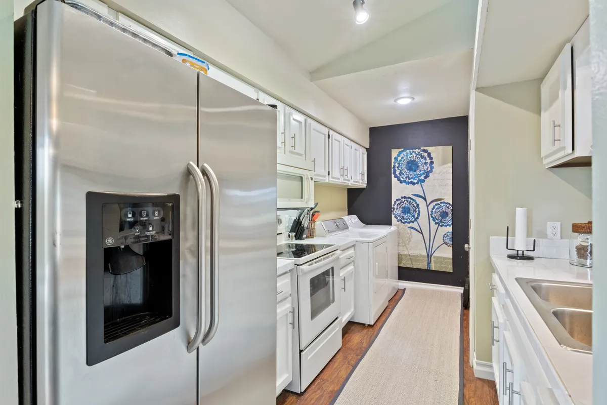 A stylish, fully equipped kitchen featuring stainless steel appliances, white cabinetry, and decorative wall art, ready for cooking with ample counter space. The design is both practical and welcoming, encouraging group meal preparation and casual entertaining.