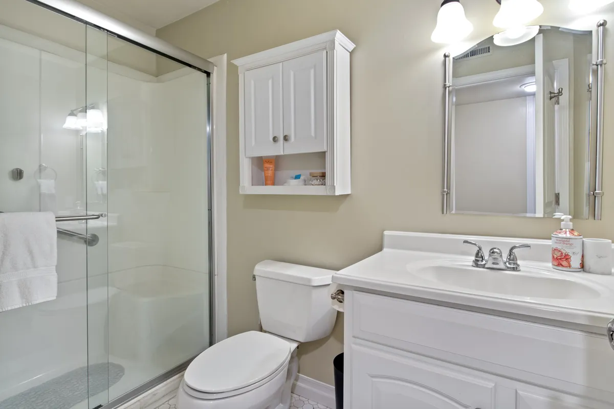A modern, well-appointed bathroom featuring a spacious shower, a sleek vanity sink with ample storage, a large mirror, and calming decorative touches. The atmosphere is refreshing and tranquil—perfect for personal routines and relaxation.